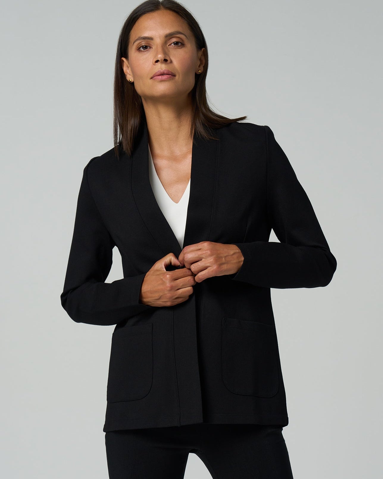 Woman wearing a black blazer over a white shirt on a gray background