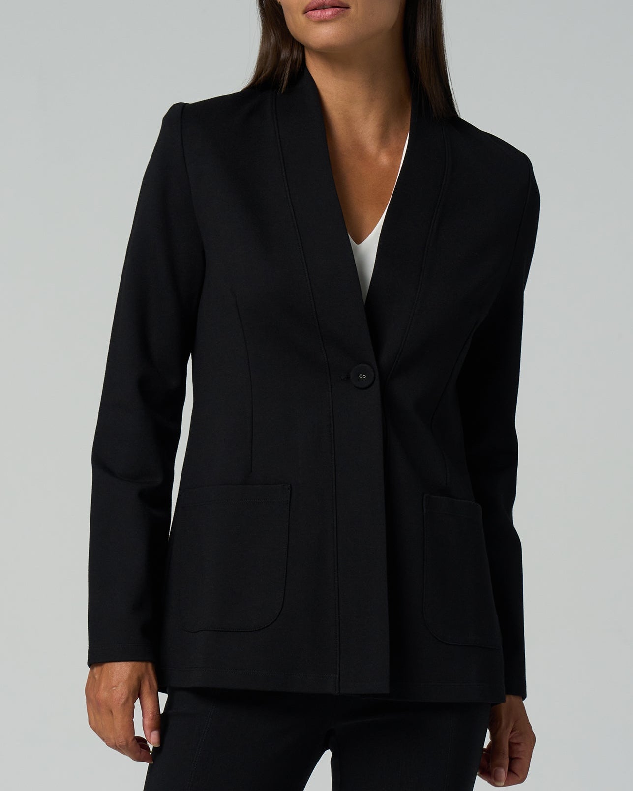 Person wearing a black blazer on a gray background