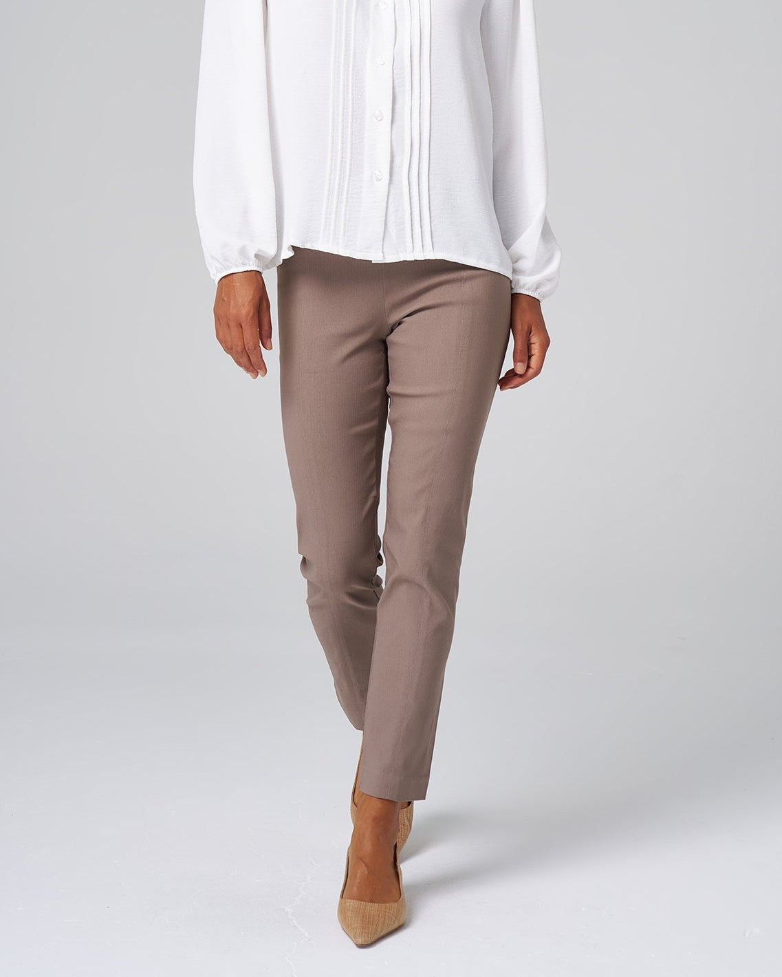 Woman wearing a white blouse and brown pants on a white background