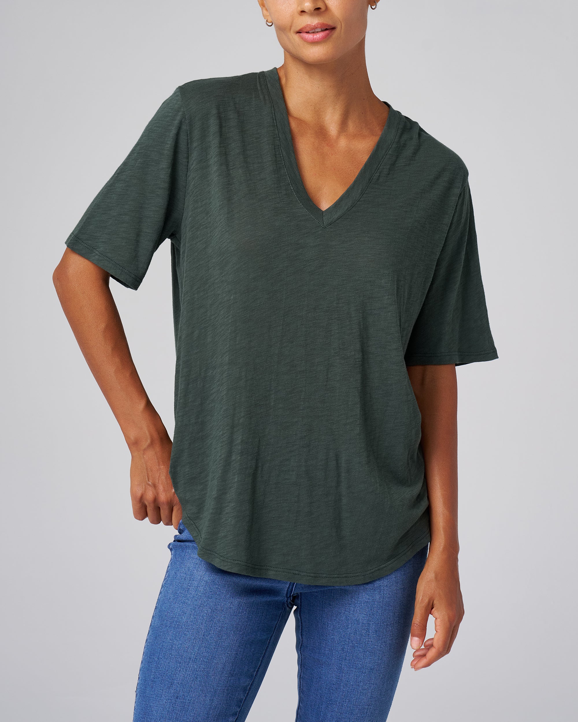 Person wearing a green t-shirt and blue jeans on a gray background