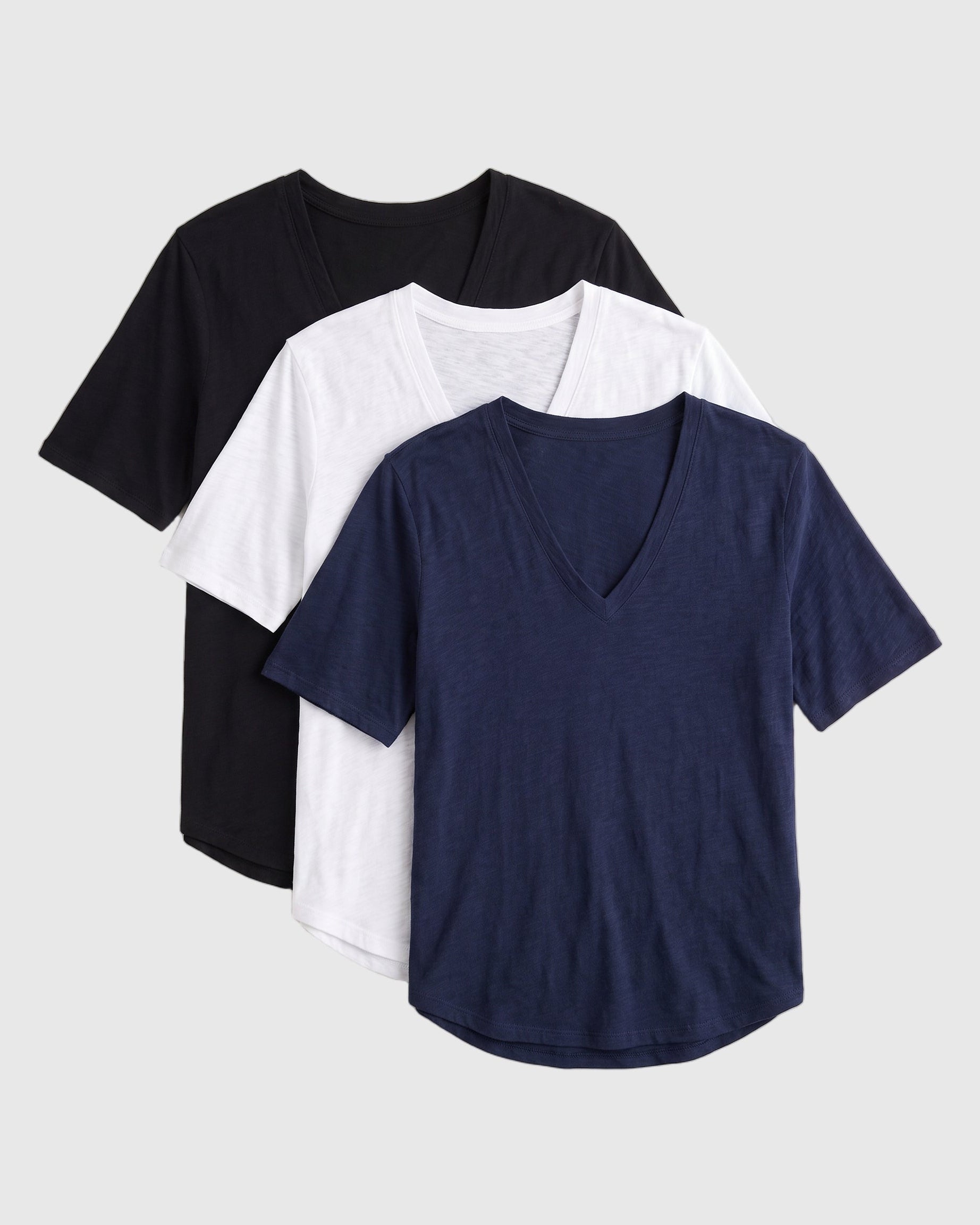 Three short-sleeve V-neck t-shirts stacked in a fan arrangement on a light gray background, shown in black, white, and navy blue.